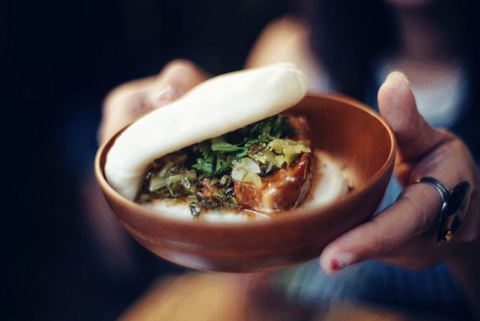 Cropped image of woman holding gua bao in container