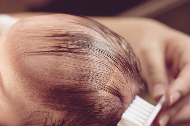 Cropped image of mother combing baby hair