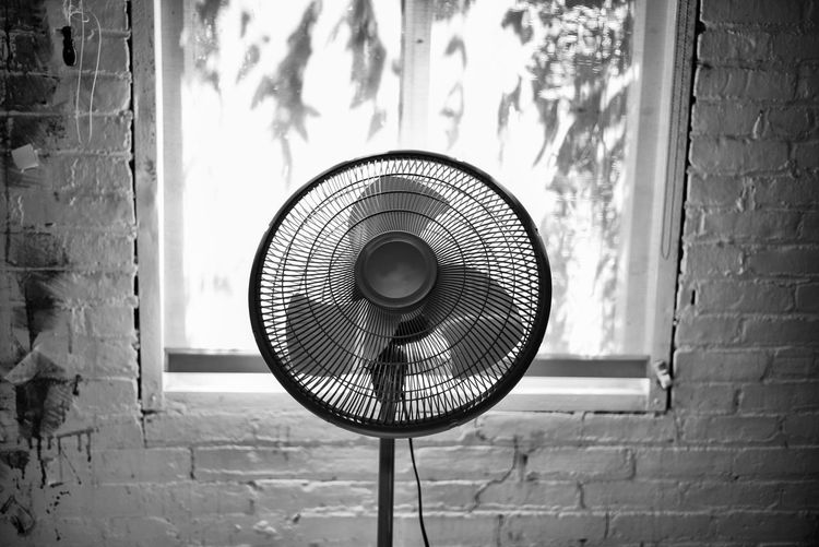 Fan inside a building in front of a window black and white