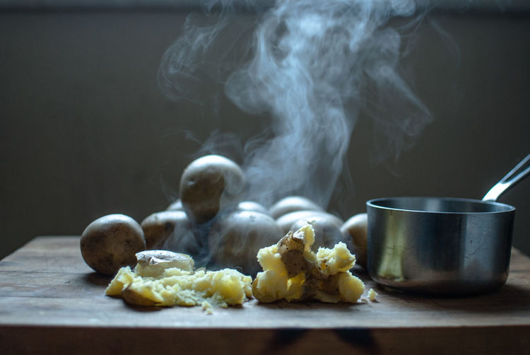 Close-up of steam emitting from boiled potato on table
