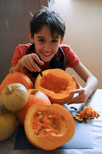 Portrait of boy with pumpkins against orange background