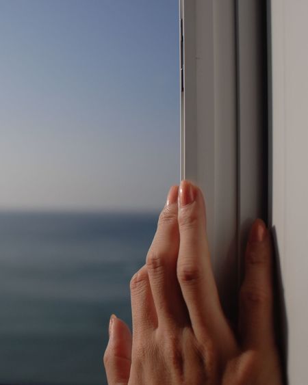 Cropped hand touching window