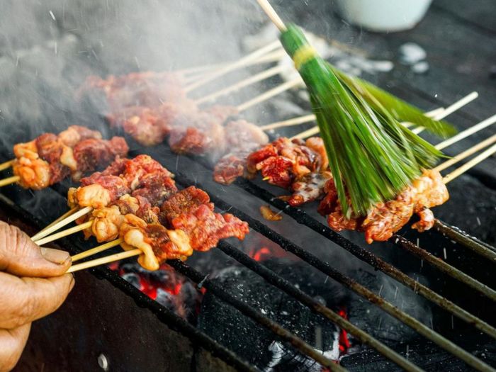 Cropped image of person preparing meat on barbecue grill