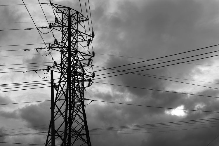 Low angle view of silhouette electricity pylon against cloudy sky