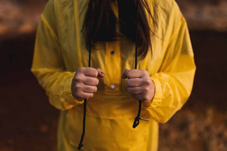 Young lady in yellow raincoat strolling in nature