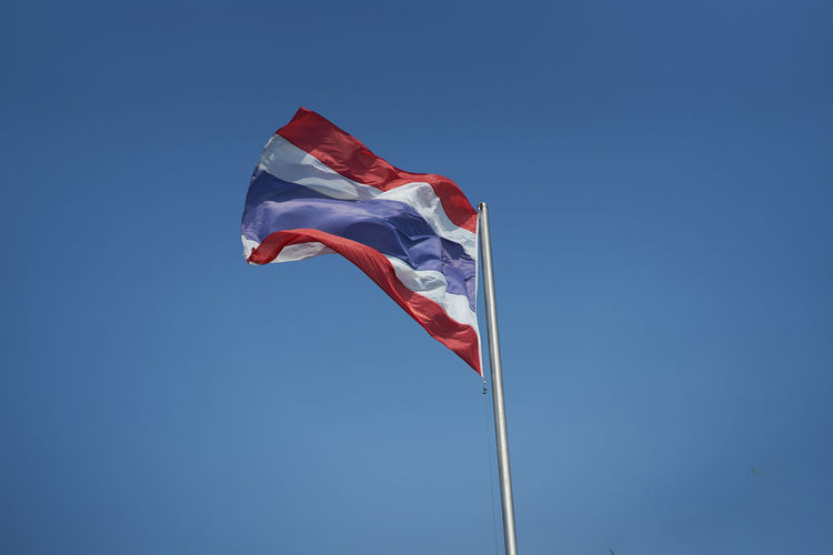 Low angle view of thailand flag against blue sky