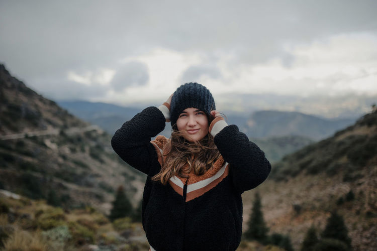 Portrait of smiling young woman standing on mountain during winter
