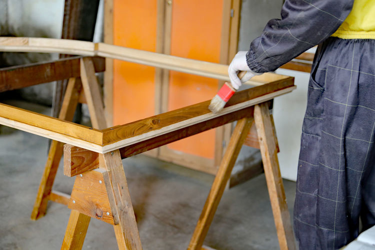 Midsection of carpenter painting wood