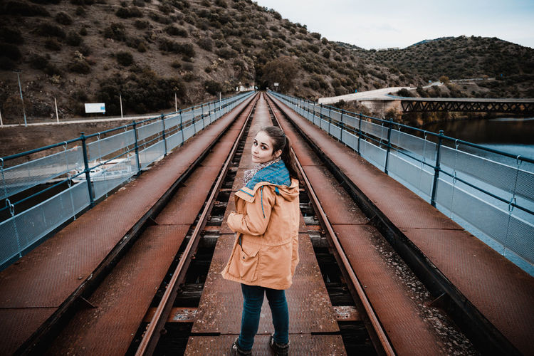 Portrait of young woman standing on railway bridge