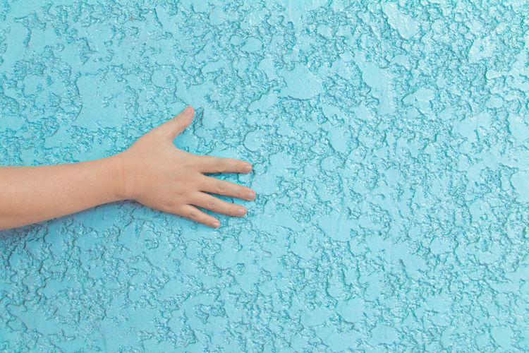 Cropped image of hand on blue textured wall