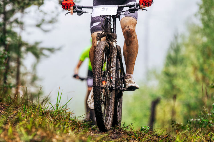 Low section of man with bicycle on dirt road