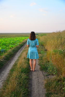 Rear view of young woman standing on field against sky