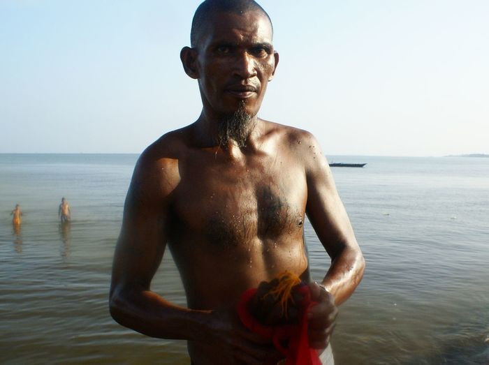 Portrait of shirtless man standing in sea