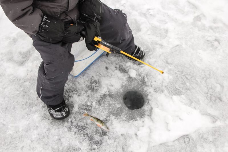 Low section of man fishing in ice