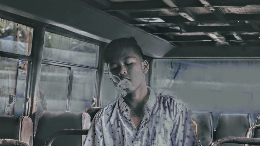 Young man smoking in abandoned bus