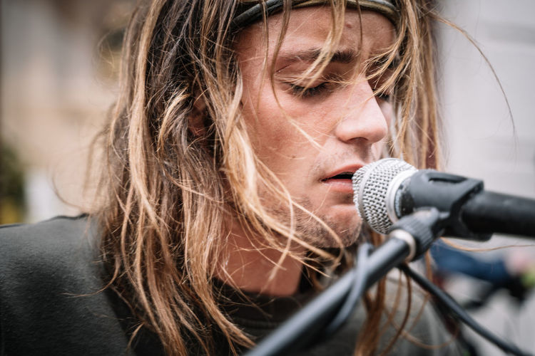 Detail of the face of a young rocker singing with emotion in the street