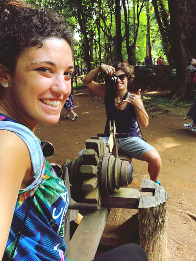 Portrait of smiling woman photographing by trees