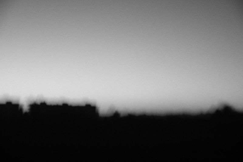 Defocused image of silhouette field against clear sky