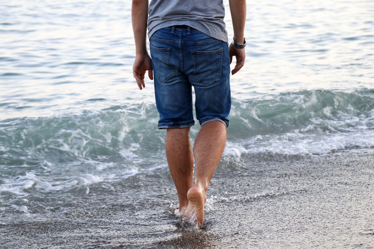 Low section of man wading in sea