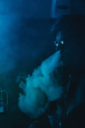 Man blowing smoke through nose at nightclub