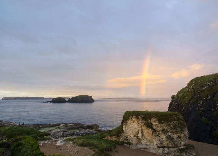 Scenic view of rainbow in sky on sea during sunset