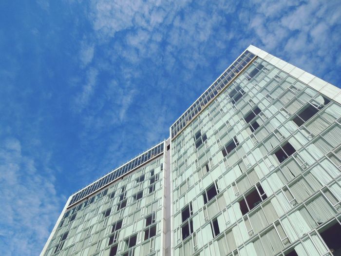 Low angle view of luxury hotel building against cloudy blue sky on sunny day