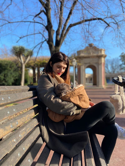 Young woman sitting on bench in park