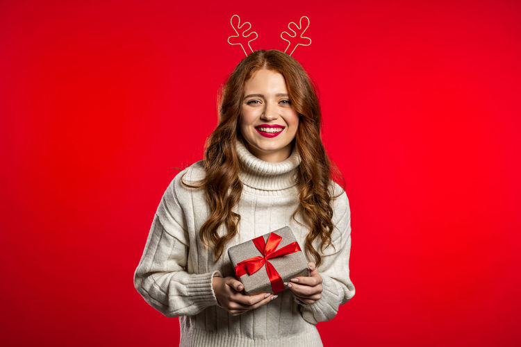 Portrait of a smiling young woman against red background