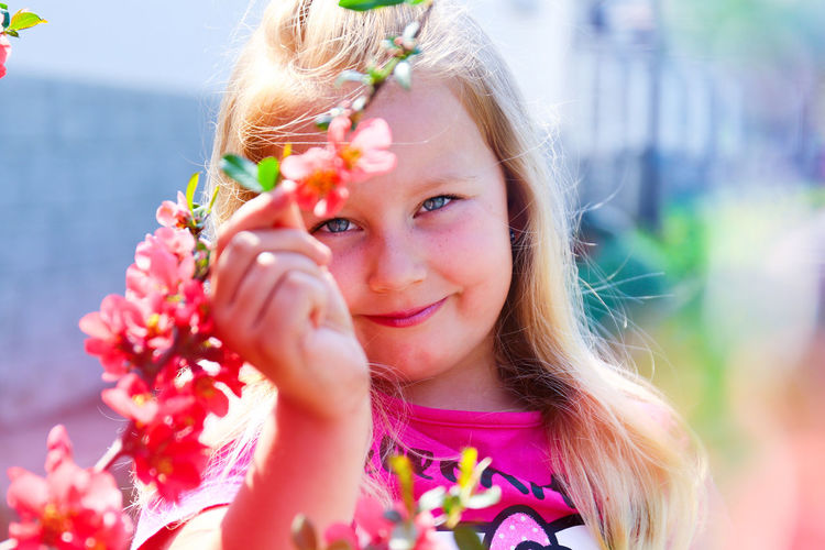 Portrait of cute smiling girl holding flowers in park