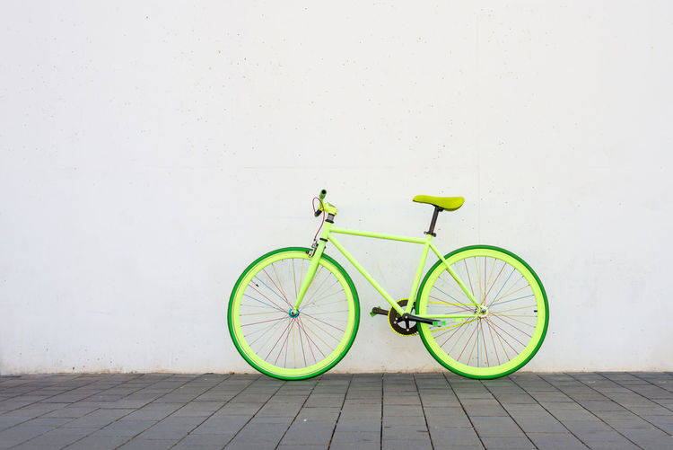 A green vintage city bicycle fixed gear on white wall