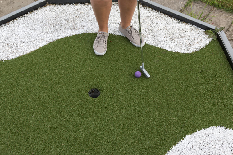 Low section of woman standing at miniature golf