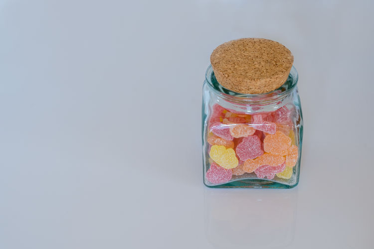 Close-up of multi colored candies on table against white background