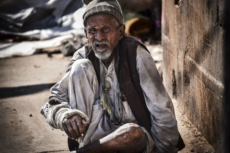 Portrait of beggar sitting on footpath