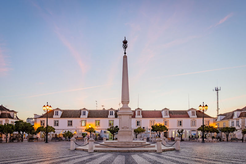 Statue in city against sky during sunset