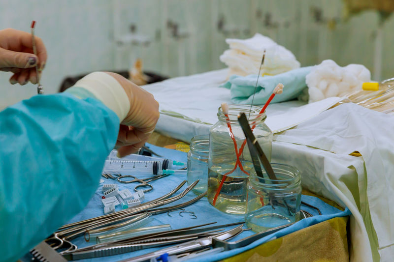 Midsection of surgeon holding surgical equipment