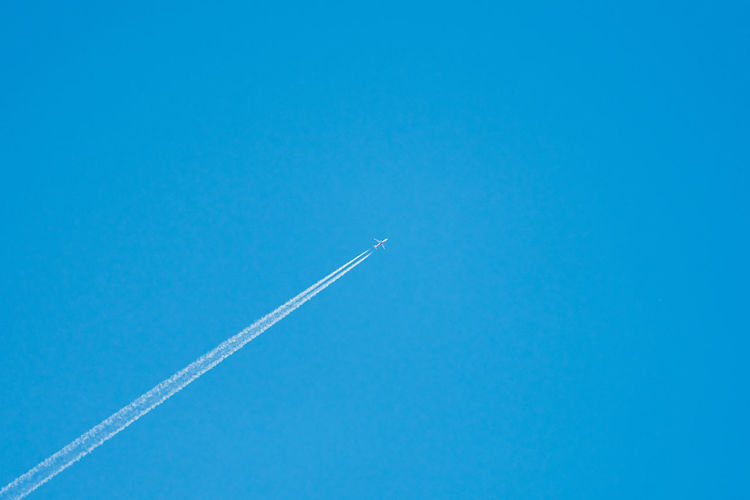 Low angle view of vapor trail against clear blue sky