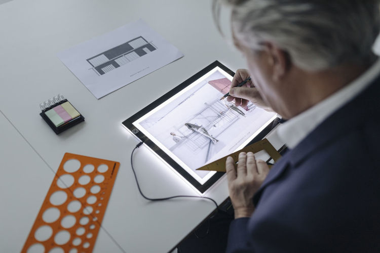 Senior businessman drawing on shining tablet