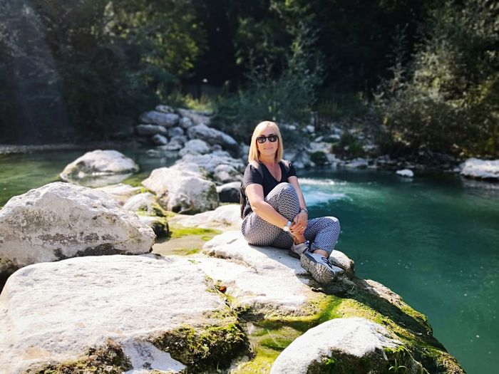 Woman sitting on rock by river in forest