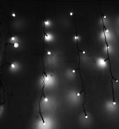 Low angle view of illuminated light bulb hanging at night
