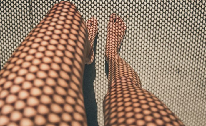 Shadow of patterned railing on woman leg