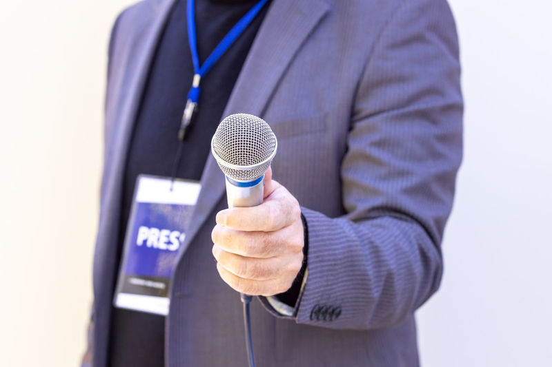 Midsection of man holding microphone against white background