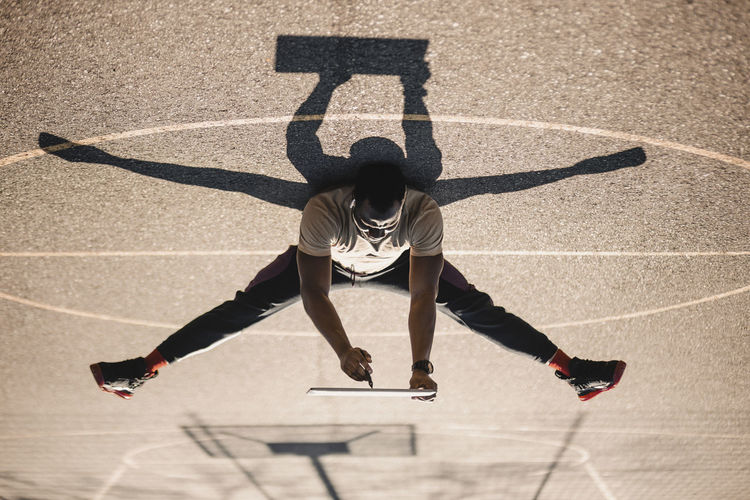 Man using digital tablet while lying on basketball court