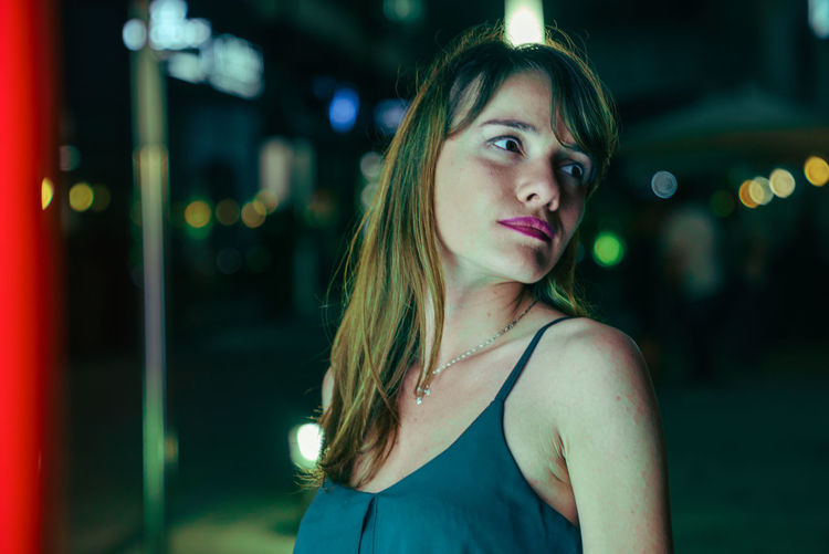 Close-up of young woman standing outdoors at night