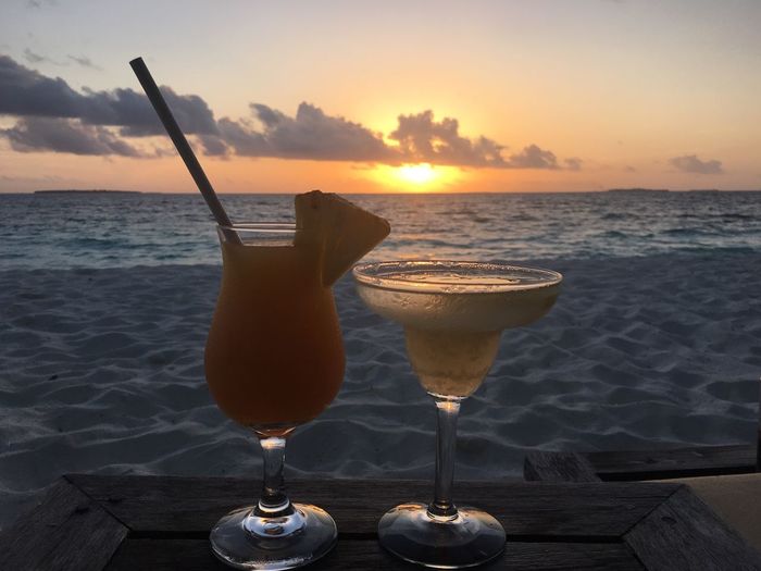 Close-up of cocktails on beach at sunset