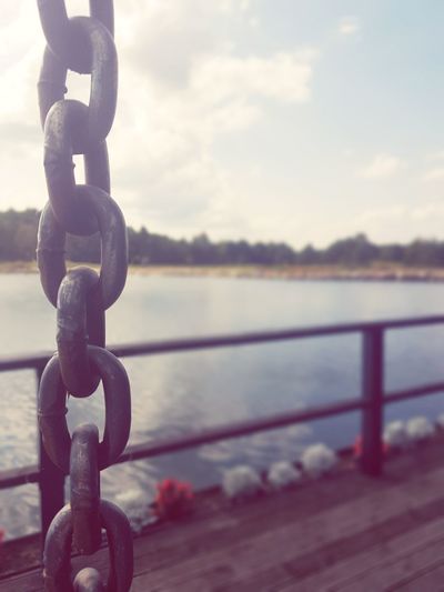 Close-up of chain on railing against sea