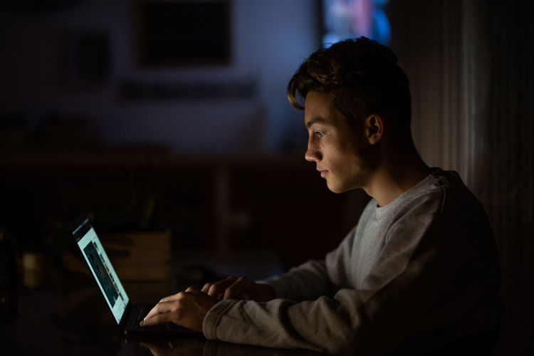 Side view of teenage boy using laptop