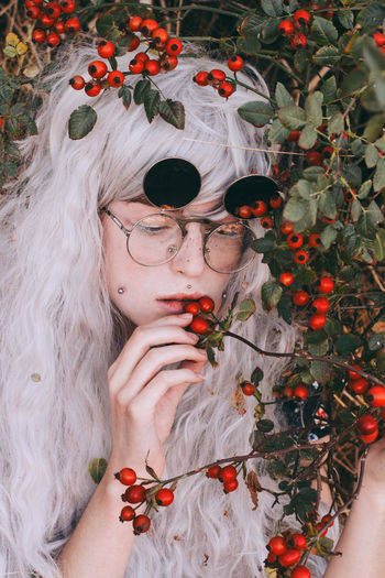 Man in gray wig smelling berries in forest
