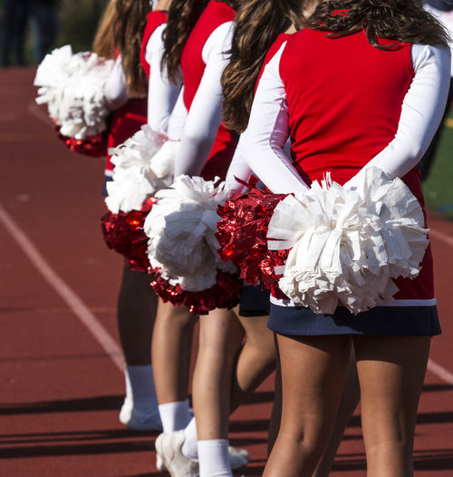 Rear view of cheerleaders holding pompoms