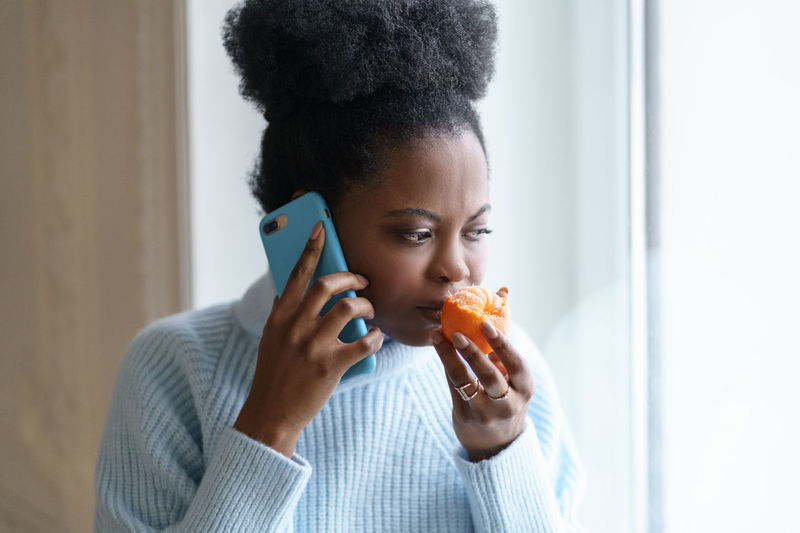 Woman smelling orange while talking over phone