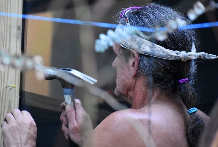 Close-up of senior man hammering on wood